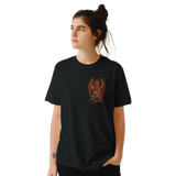 A woman wearing a black short-sleeve t-shirt with a small orange graphic of a winged creature on the left chest, set against a plain white background.