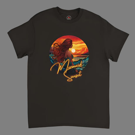 A black T-shirt with a printed design featuring a mermaid sitting on a surfboard under a sunset sky.