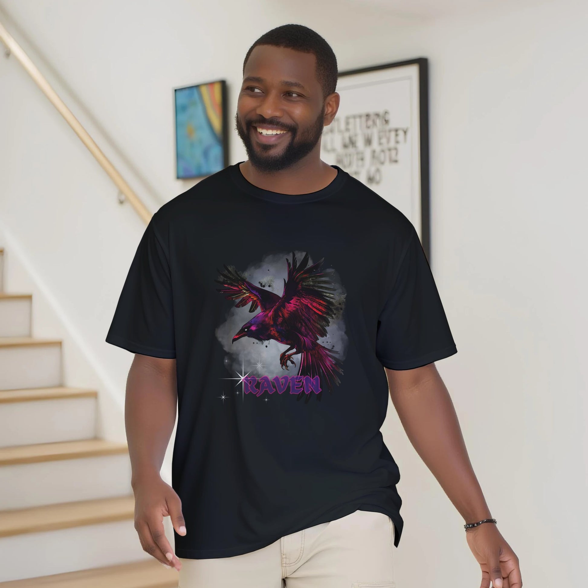 A man wearing a black t-shirt with a colorful raven design indoors.