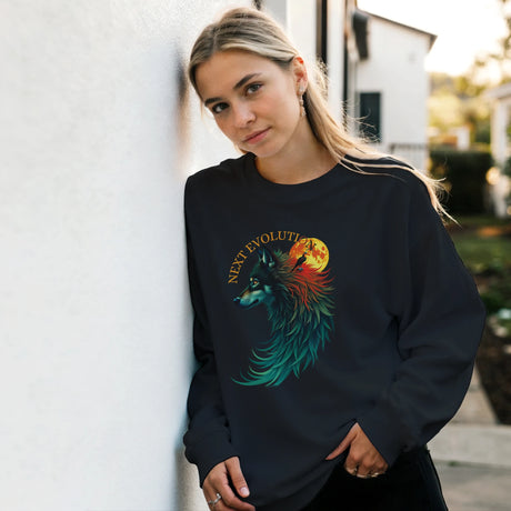 A woman wearing a black crewneck sweatshirt with a colorful graphic of a wolf and a red/orange moon, leaning against a white wall outdoors.