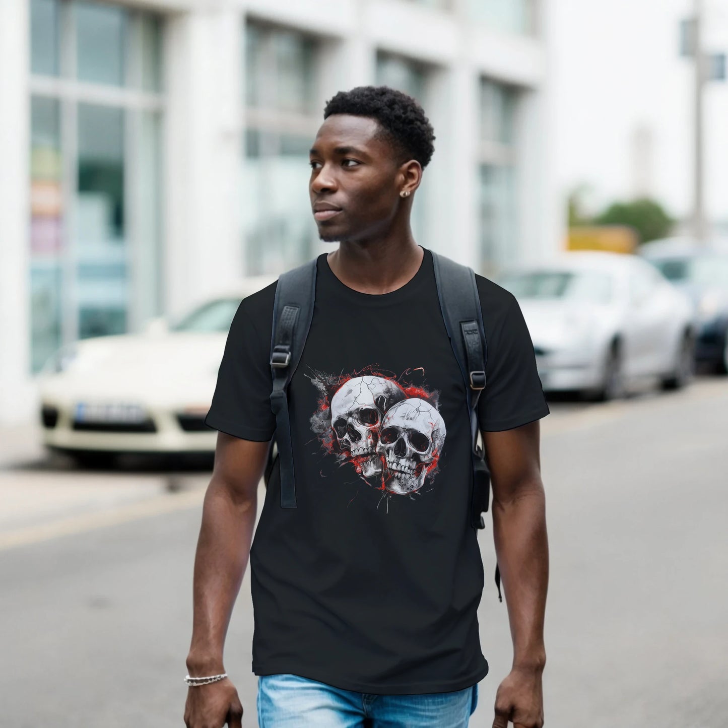 A man wearing a black t-shirt with a skull design is walking on a street.