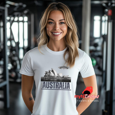 Front view of a Young woman standing in a gym wearing a white soft casual tee showing the Sydney Opera House sails with a sleek spaceship graphic orbiting overhead, printed on ultra-soft Gildan 64000 cotton.T-shirt