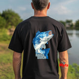 Man wearing a black t-shirt with a blue fish graphic and 'Barra Baron' text, standing by a body of water.
