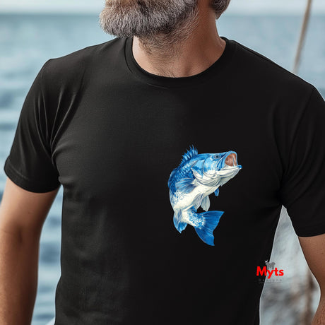 Person wearing a black t-shirt with a blue fish graphic, standing by water.