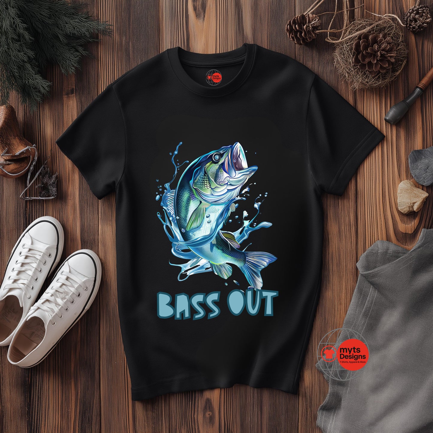 Black t-shirt with a blue bass graphic and 'BASS OUT' text on a wooden surface with shoes and a gray shirt.