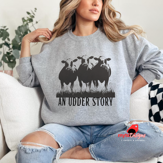 Person wearing a gray sweatshirt with cow graphic and 'An Udder Story' text, sitting on a couch.