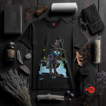Black t-shirt with a colorful graphic of a witch on a dark wooden surface with Halloween-themed decorations.