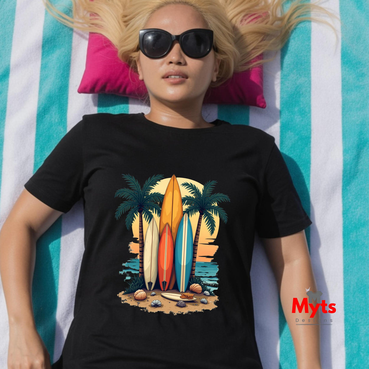 Person wearing a black t-shirt with a beach-themed design, lying on a striped towel.