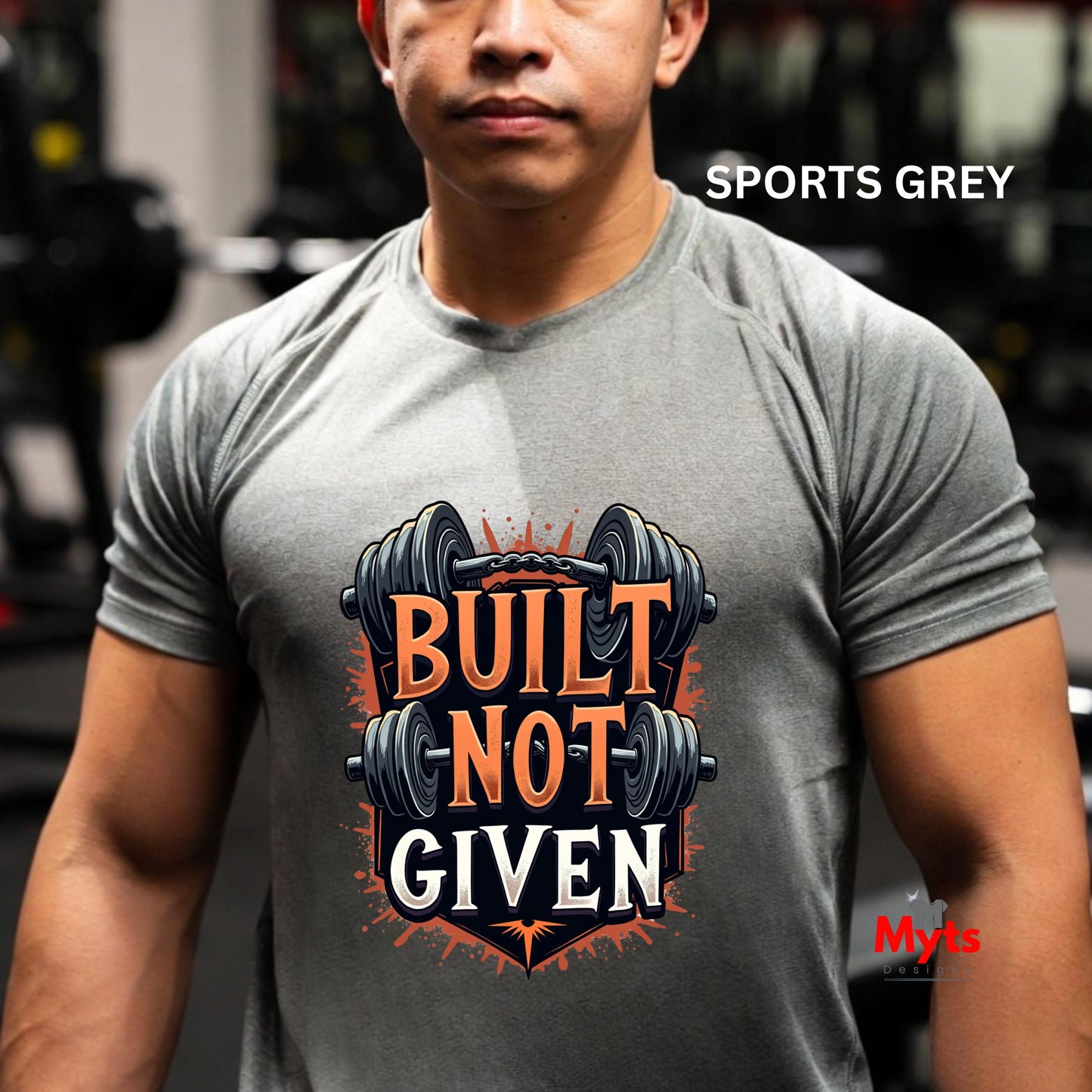 Person wearing a gray t-shirt with 'Built Not Given' graphic and weights in a gym setting.