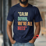 A man wearing a navy retro-style casual tee featuring bold distressed vintage typography reading “Relax — We’re All Weird Here,” printed on ultra-soft Gildan 64000 cotton.

