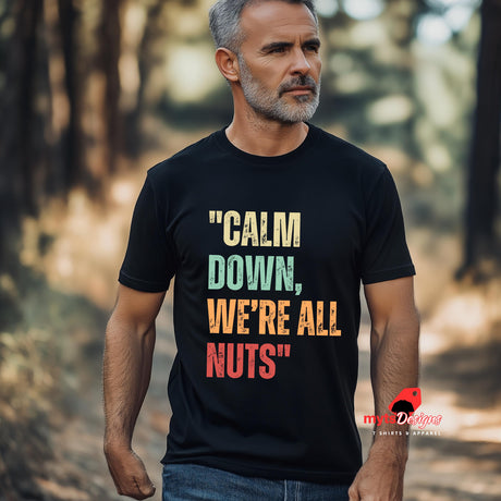 A senior man walking in the woods wearing a black retro-style casual tee featuring bold distressed vintage typography reading “Relax — We’re All Weird Here,” printed on ultra-soft Gildan 64000 cotton.

