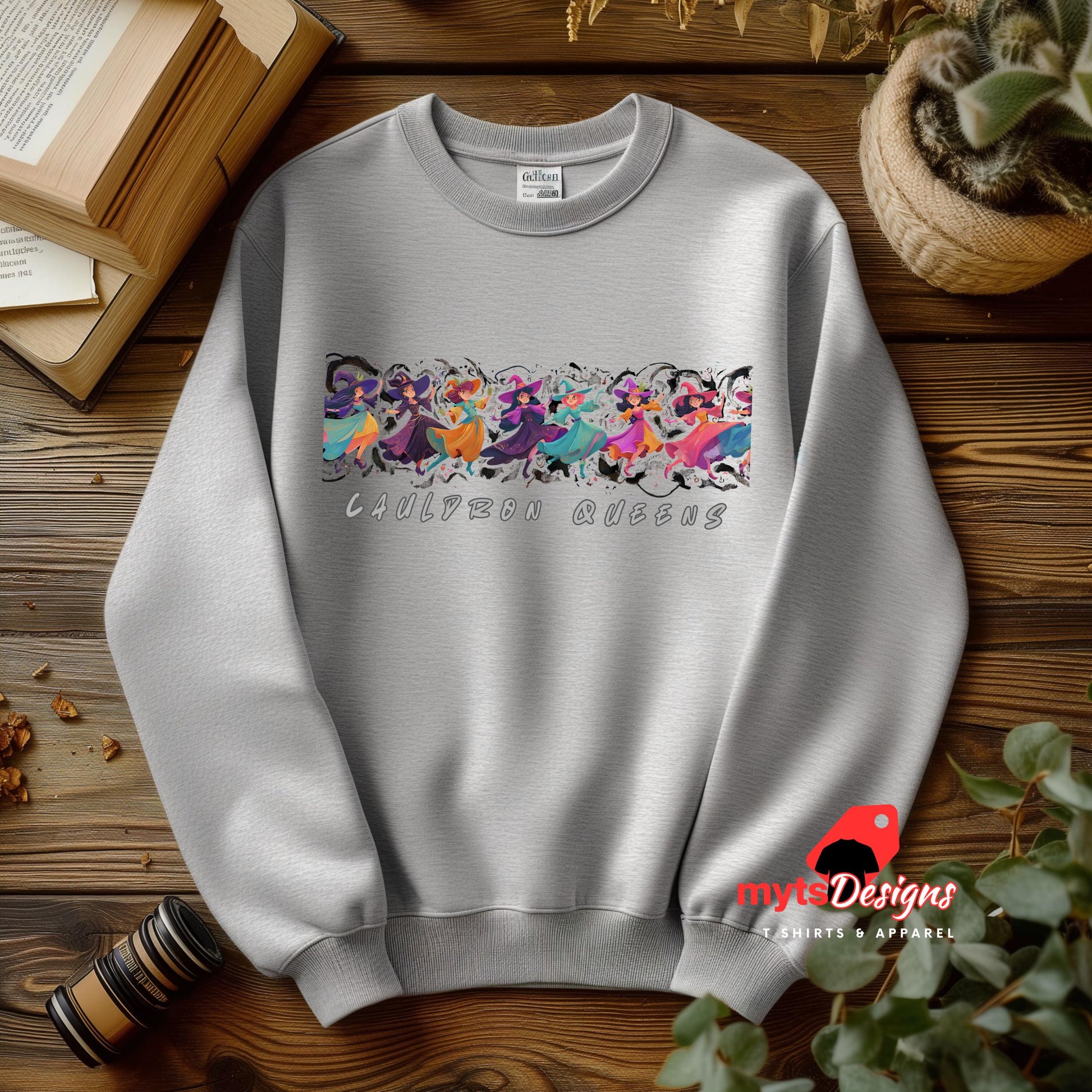 Gray sweatshirt with colorful graphic design on a wooden surface, featuring 'myts Designs' branding.