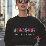 Person wearing a black sweatshirt with 'Cauldron Queens' design and sunglasses, standing in an urban setting.