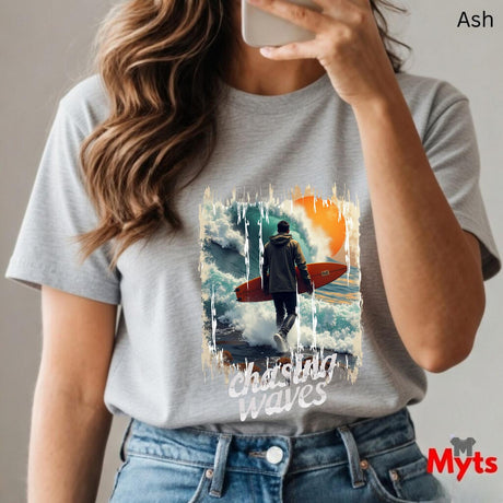 Person wearing a ash t-shirt with a graphic design and text, holding a phone.