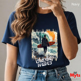Person wearing a navy t-shirt with a graphic design and text, holding a phone.