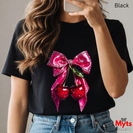 Person wearing a black t-shirt with a pink bow and red cherries design, holding a phone.