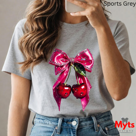 Person wearing a gray t-shirt with a pink bow and red cherries design, taking a selfie.