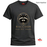 A dark heather charcoal gray t-shirt with a graphic of a raccoon's face and the text 'RACCOON STAY WILD' in a metallic gold tone. The brand name 'Myts' is visible on the inner neck label and as a watermark logo in the bottom right corner.