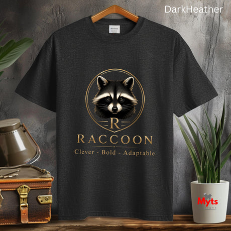 A dark heather gray graphic t-shirt hanging on a wooden hanger against a textured gray wall. The shirt features a gold and white raccoon logo with the text 'R RACCOON Clever - Bold - Adaptable'.
