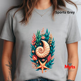 A person wearing a light gray short-sleeve t-shirt with a colorful seashell and coral graphic on the front. The text 'Sports Grey' is visible in the top right, and a 'Myts Designs' logo is visible in the bottom right.