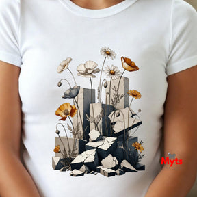 A white short-sleeve crewneck t-shirt featuring a detailed graphic print of wildflowers blooming from broken gray stone blocks. The shirt is shown on a model, with the brand name 'Myts' printed in red on the lower right side of the graphic.