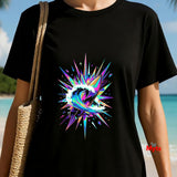 Person wearing a black t-shirt with a colorful abstract design on a beach.