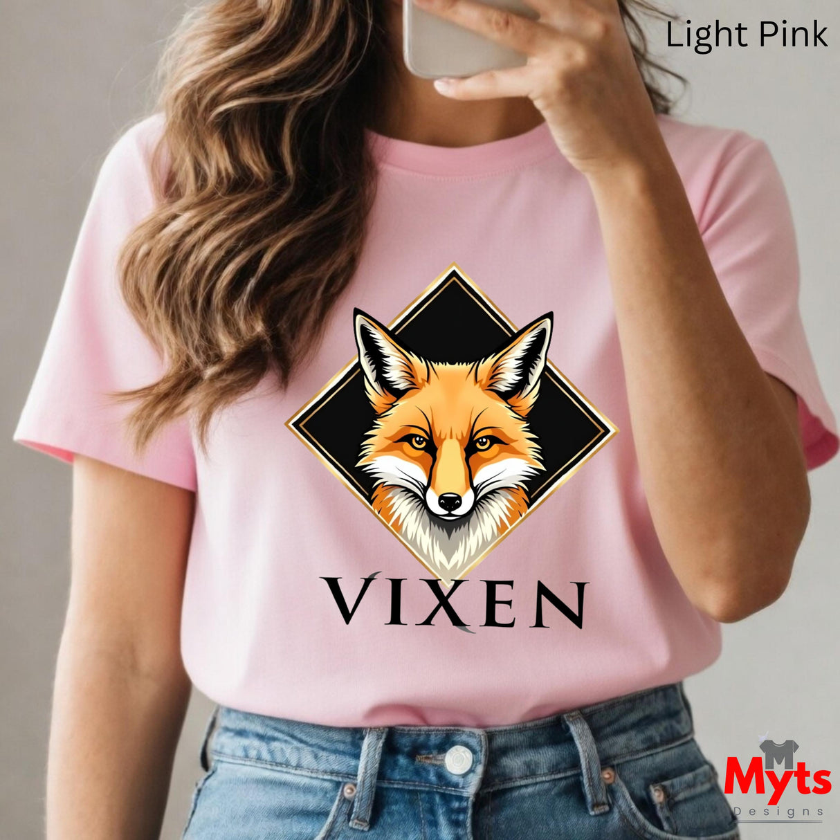 Person wearing a pink t-shirt with a fox graphic and 'VIXEN' text, holding a phone.