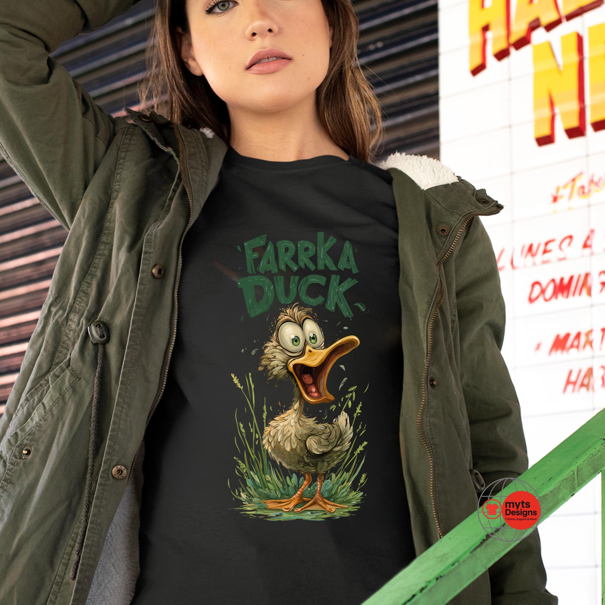 Person wearing a black t-shirt with a cartoon duck graphic and text, standing in front of a colorful wall.