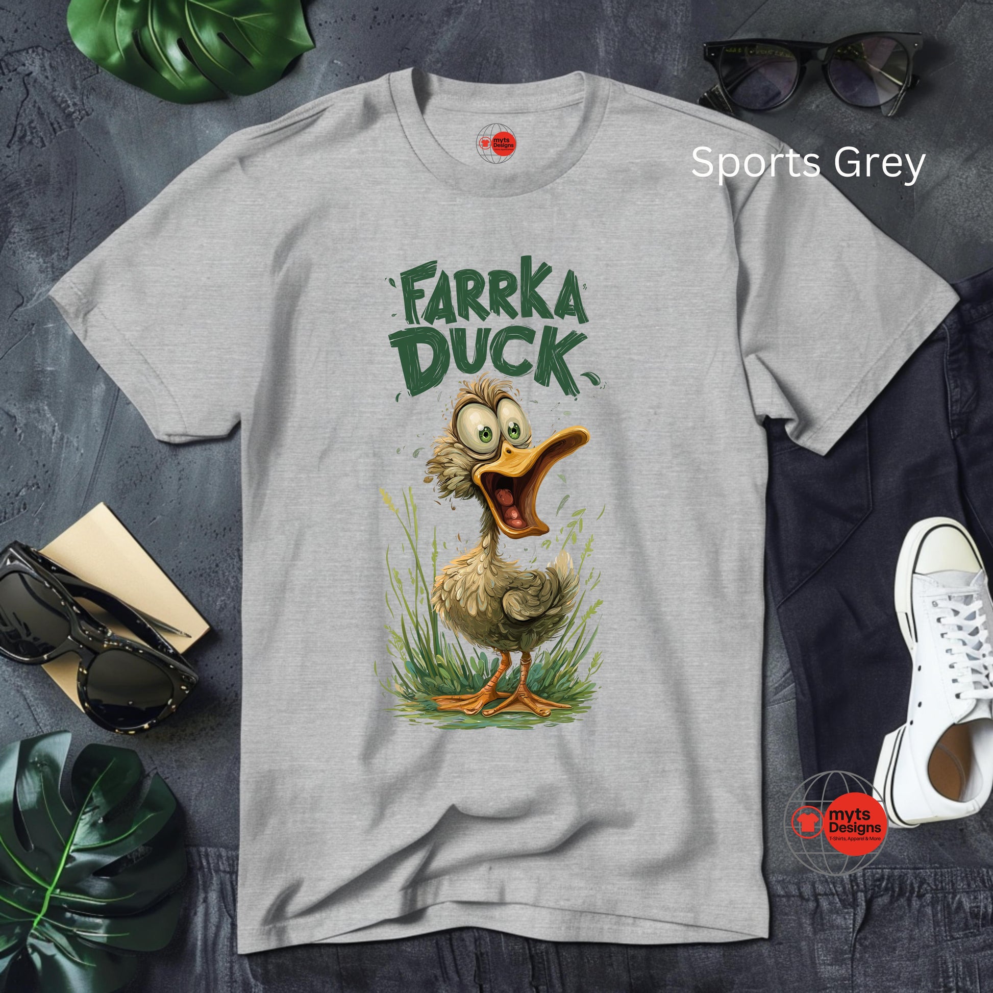 Gray t-shirt with a cartoon duck design and text on a gray surface with accessories.