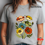 A person wearing a light gray short-sleeve T-shirt with a colorful poppy floral graphic on the front. The text 'Sports Grey' appears near the upper right, and a red 'Myts' logo watermark is visible in the lower right corner.