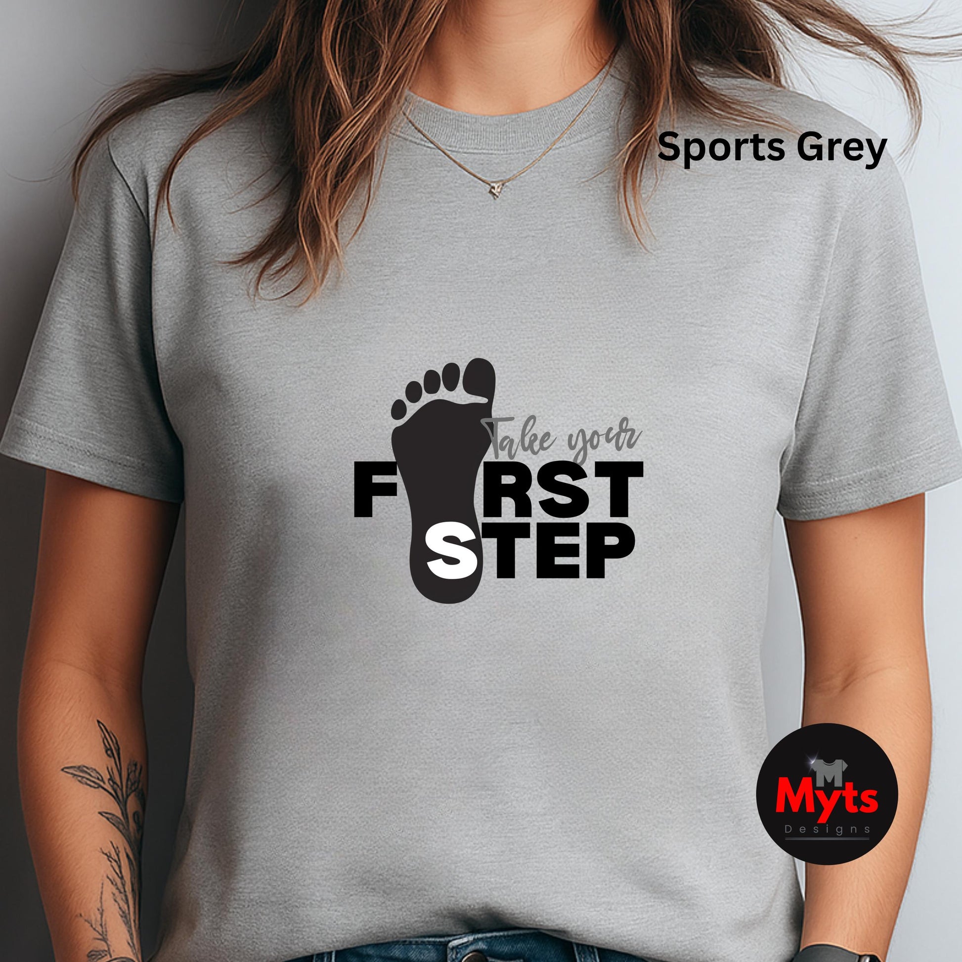 Gray t-shirt with a black footprint design and text 'Take your first step' on a plain background.