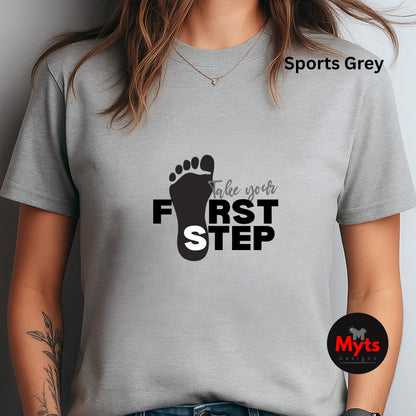 Gray t-shirt with a black footprint design and text 'Take your first step' on a plain background.
