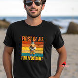 A man at the beach wearing a black "first of all I'm a delight" funny donkey t-shirt