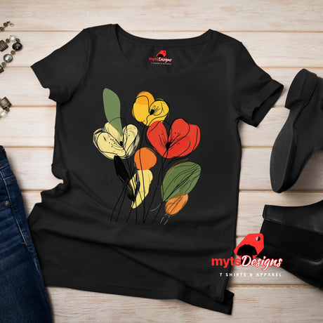 Black t-shirt featuring minimalist floral line art with abstract red, yellow, and orange flowers and green leaves, laid flat on a wooden surface with rolled sleeves.