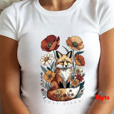 A white short-sleeve crewneck t-shirt featuring a colorful graphic of a fox surrounded by flowers, with the text 'FOXY VIXEN' printed below. The shirt is shown on a model.