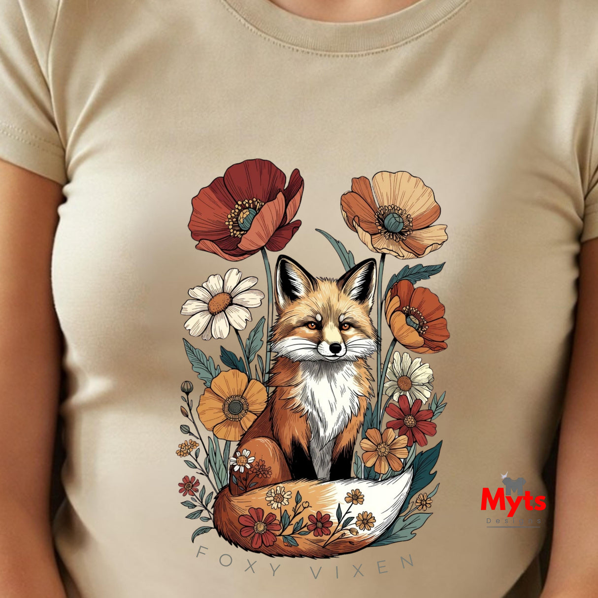 A close-up of a Natural t-shirt featuring a colorful graphic of a fox surrounded by wildflowers, with the text 'FOXY VIXEN' printed below. A red 'Myts' logo is visible in the bottom right of the graphic.