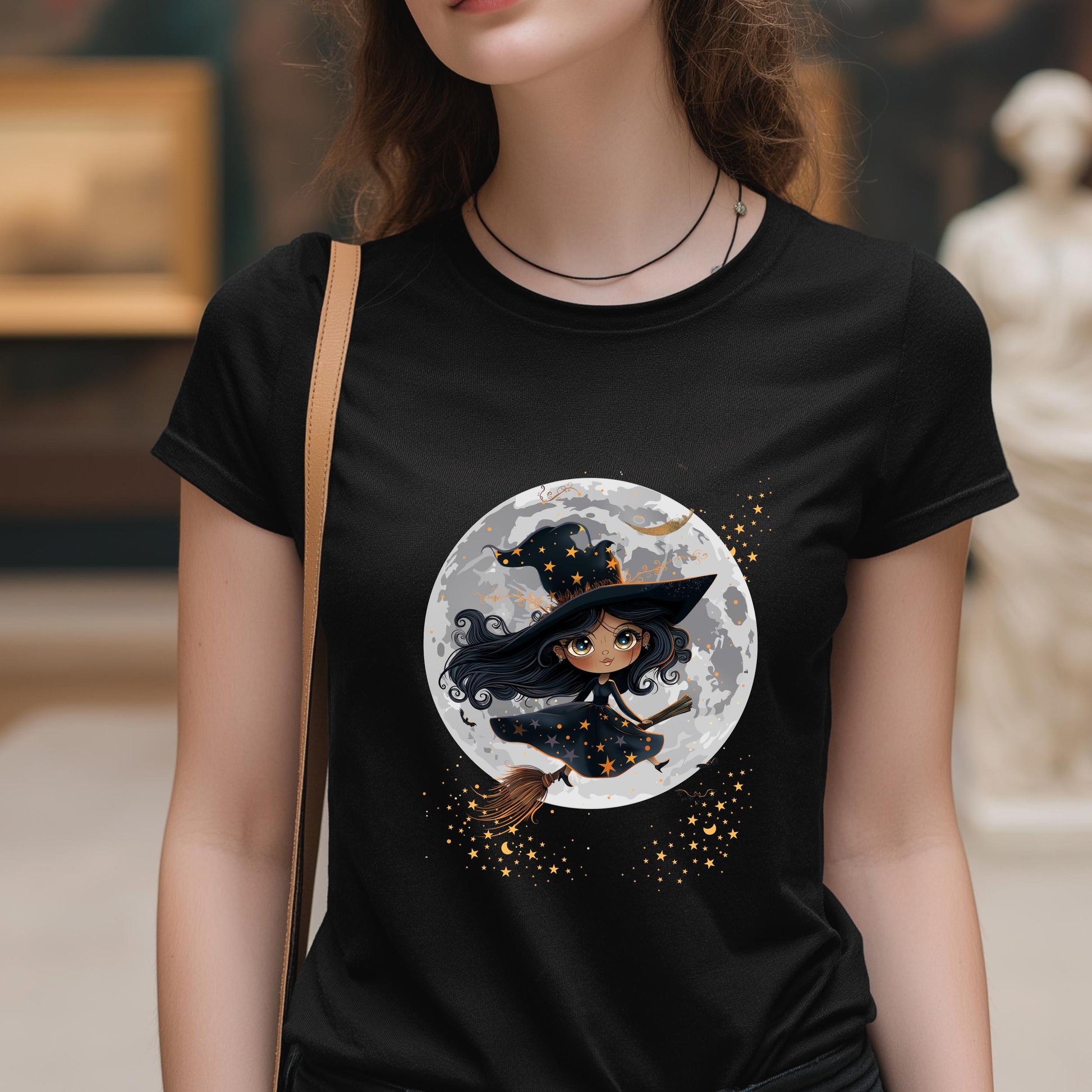 Person wearing a black t-shirt with a witch graphic on a full moon background