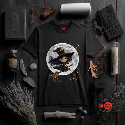Black t-shirt with a witch graphic on a dark wooden surface with Halloween-themed decor.