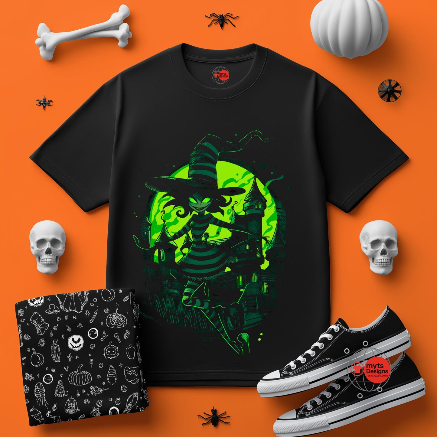 Black t-shirt with green witch design on an orange background with Halloween-themed accessories.