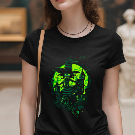 Person wearing a black t-shirt with a green graphic design of a witch and pumpkin.