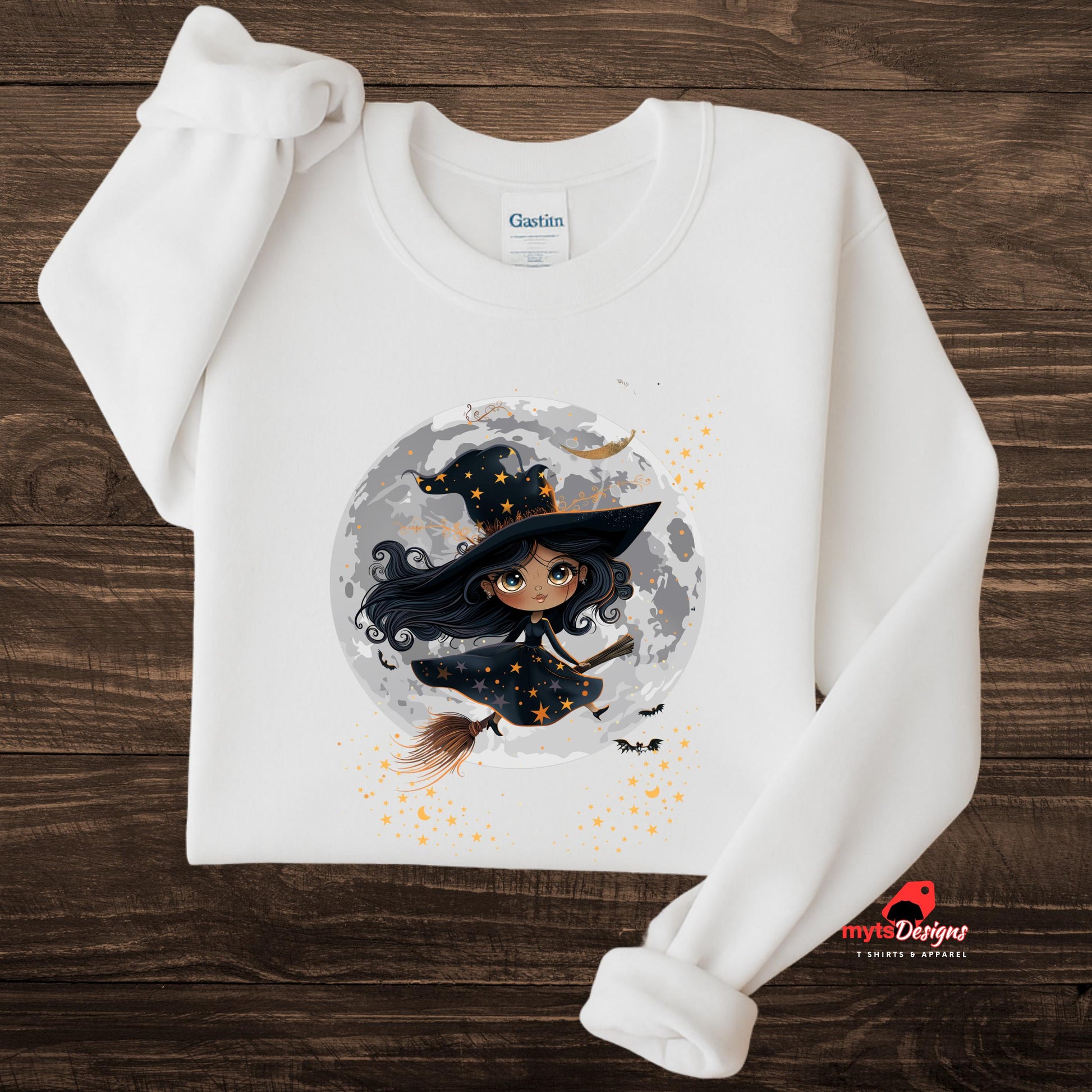 White sweatshirt with a witch graphic on a wooden surface