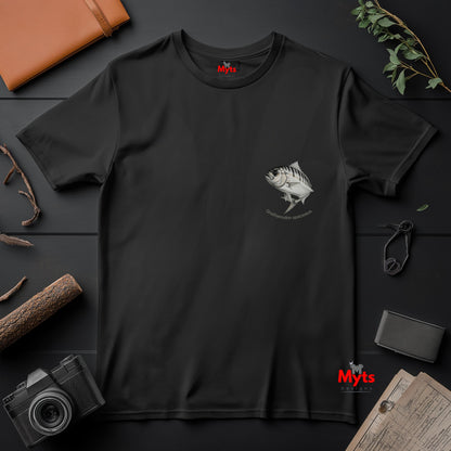 Black t-shirt with a fish graphic on a dark surface with a camera and wallet.