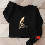 Black sweatshirt with a gold abstract design on a wooden floor