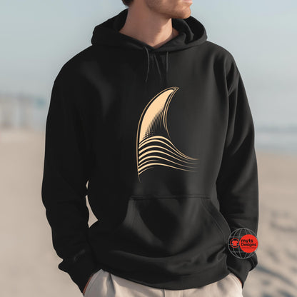 Person wearing a black hoodie with a gold abstract design on a beach.
