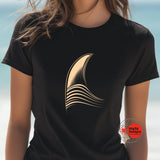 Black t-shirt with a gold abstract design on a blurred beach background