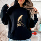 Person wearing a black hoodie with a gold design, sitting in a room.