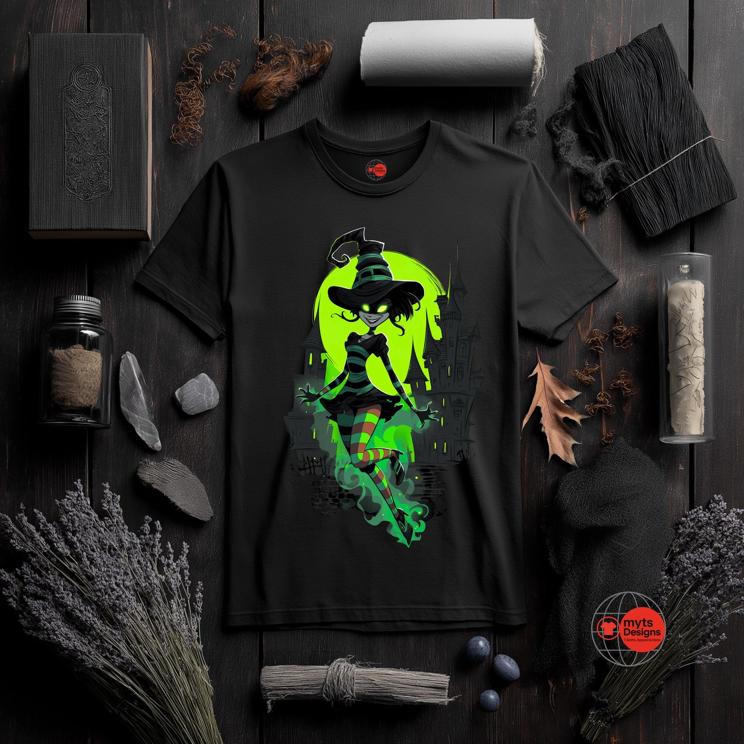 Black t-shirt with a green witch graphic on a dark wooden surface with decorative items.