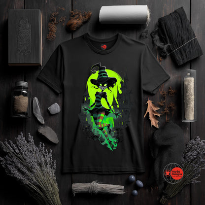 Black t-shirt with a green witch graphic on a dark wooden surface with decorative items.