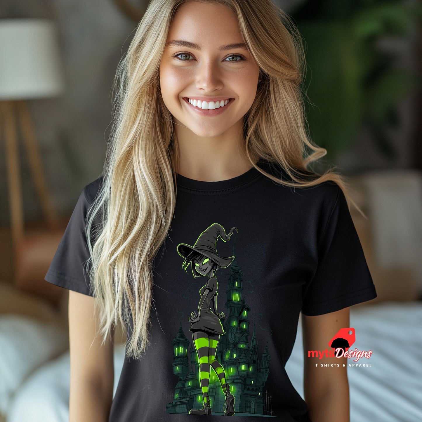 Model wearing a black T-shirt featuring a glowing green-eyed witch with striped neon stockings, standing confidently in front of a gothic, haunted tower. Halloween-themed design with a dark, edgy, and playful aesthetic. Logo: MytsDesigns.