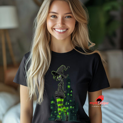Model wearing a black T-shirt featuring a glowing green-eyed witch with striped neon stockings, standing confidently in front of a gothic, haunted tower. Halloween-themed design with a dark, edgy, and playful aesthetic. Logo: MytsDesigns.